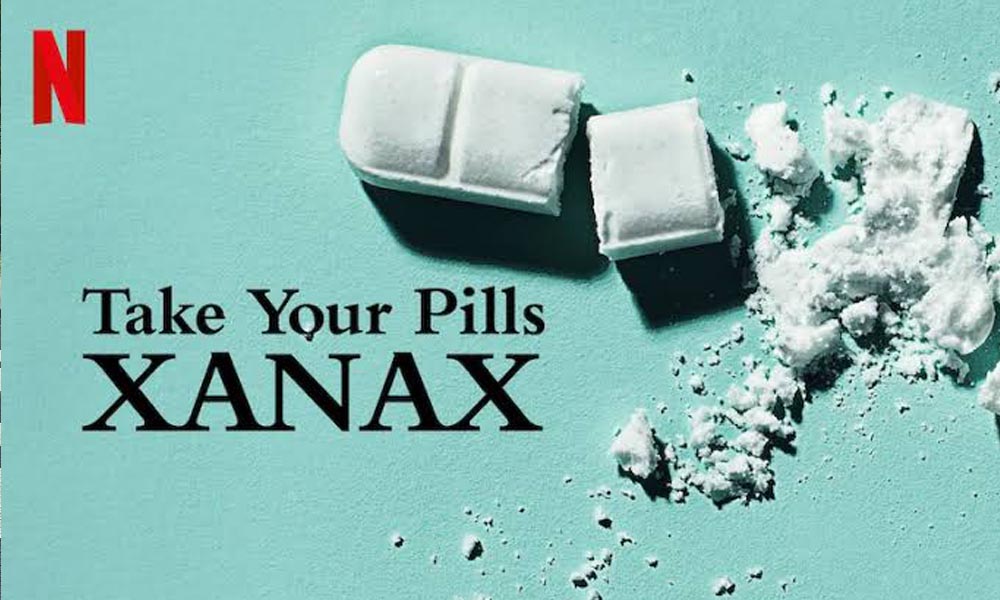 Fotografija bele tablete Ksanaks slomljene na nekoliko komada sa belim prahom na tirkiznoj pozadini, sa crvenim Netflix logom i naslovom „Take Your Pills: Xanax“.